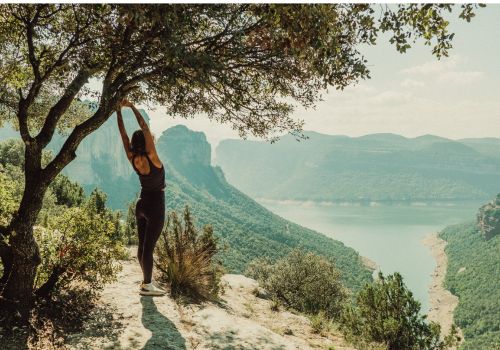 Femme d'étirant devant beau paysage, évoquant le bien-être et la clarté mentale retrouvée